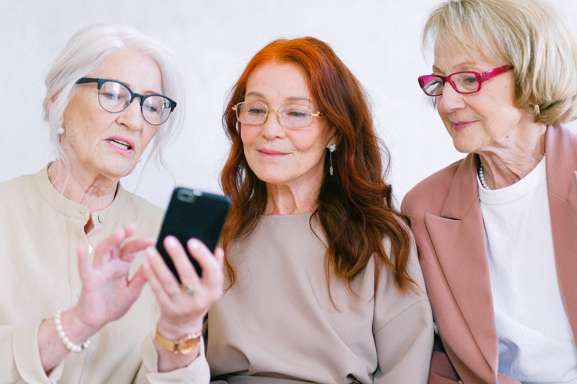 Three senior women looking at a smart phone together.